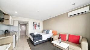 Ein Hotelzimmer mit einer Küchenzeile, einem Bett, einer Couch und einem Couchtisch.