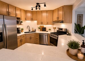 A modern kitchen with wooden cabinets, stainless steel appliances, and a marble countertop. - Serene 4-bedroom house with AC in lovely Las Vegas with Private Pool and Sauna (Las Vegas)