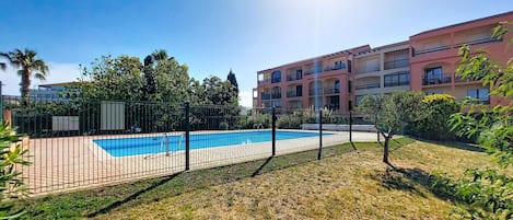 Una piscina rodeada por una cerca, con un edificio al fondo.