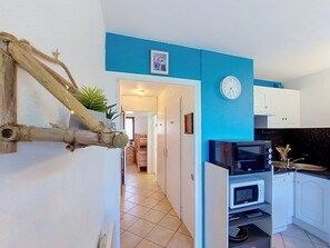 Une cuisine avec des meubles blancs, un four à micro-ondes, un grille-pain et une horloge au mur.
