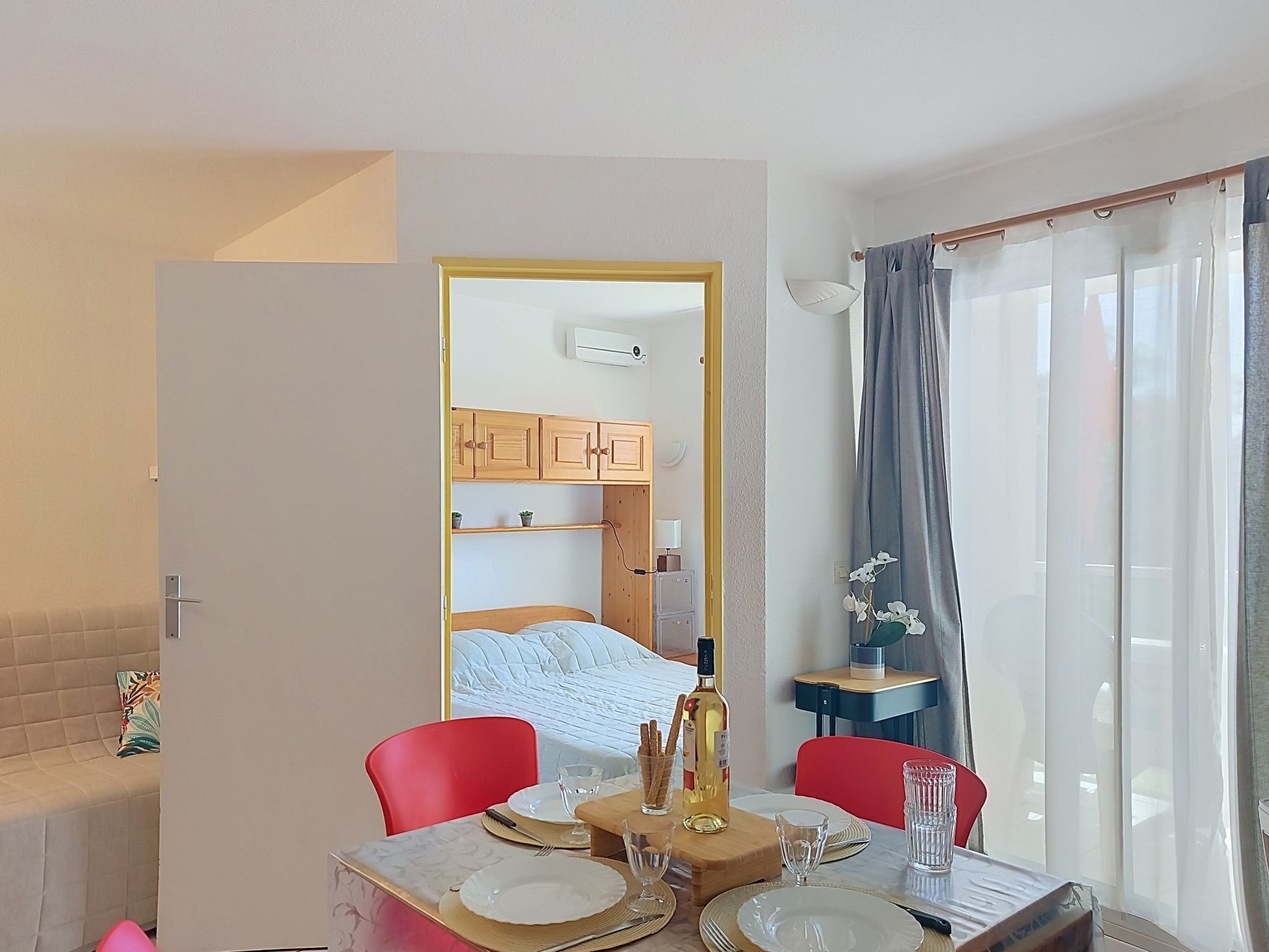 Hotelkamer met een zithoek, een bed, een kleine tafel met een fles en een raam met gordijnen.