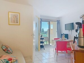 A room with a bed, a dining table with chairs, a TV, and a balcony with a view. - Les Goelettes by Interhome (Saint Cyprien)