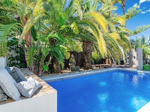 A swimming pool surrounded by tropical plants and a stone statue. - Villa La Calma by Interhome (Jávea)