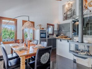 En matplats med ett träbord, svarta stolar och en hängande lampa.