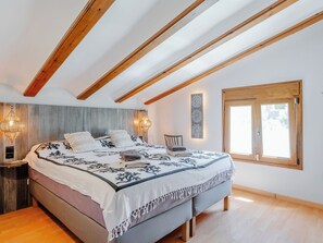 A bedroom with a bed, wooden beams, a wall-mounted light, a window, and a bedside table. - Villa La Calma by Interhome (Jávea)