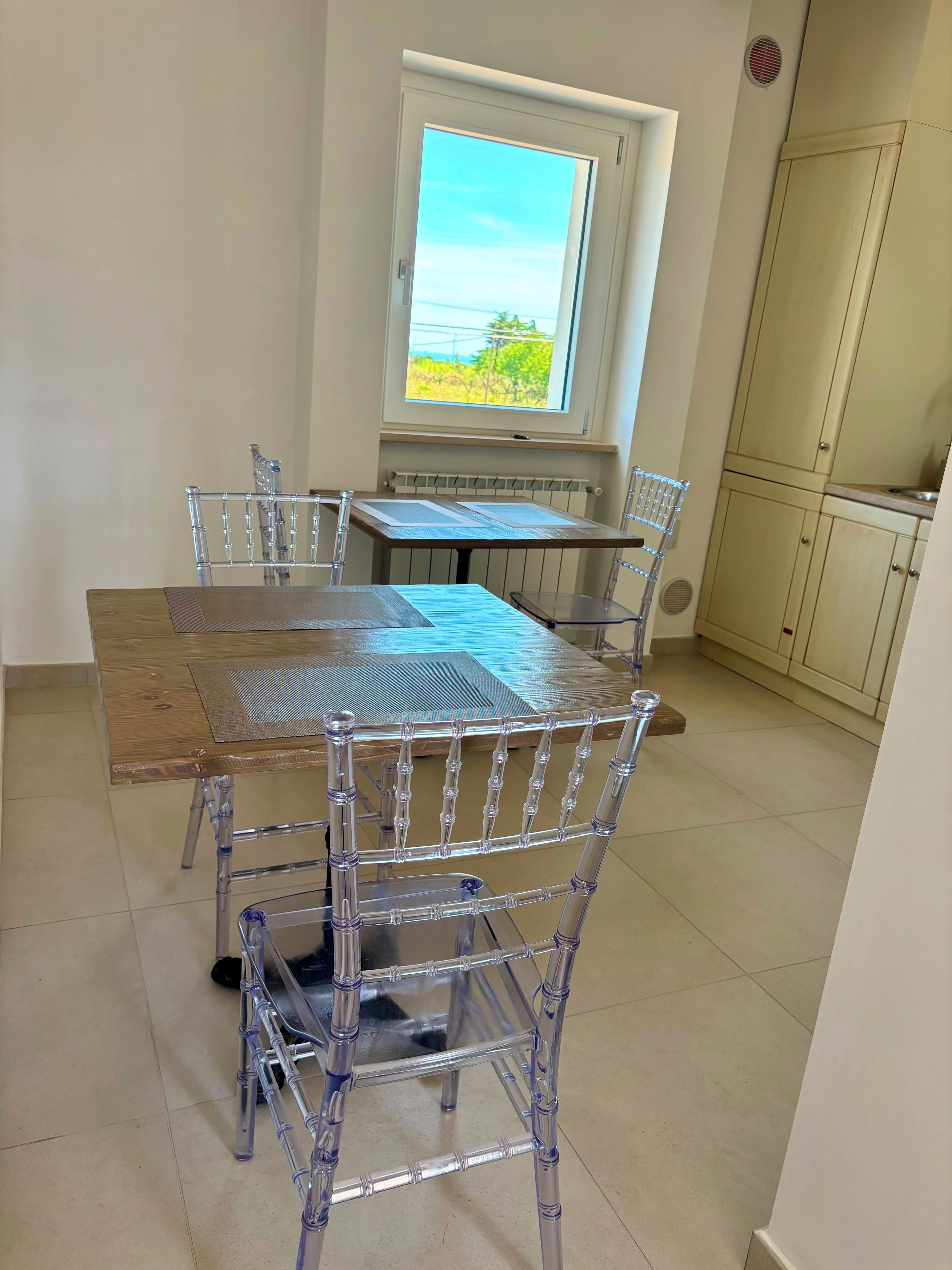 A dining area with a table and chairs, a window with a view, and a kitchen area.
