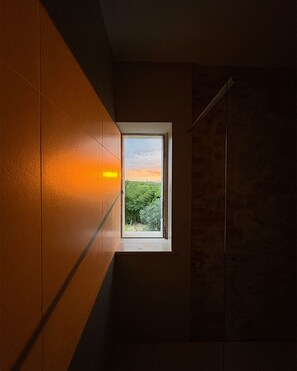 A room with a window, a towel rack, and a wall with a textured pattern.