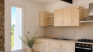 A modern kitchen with a wooden table and chairs, a stove, and cabinets. - Tenuta Ferrante Relais (Abruzzo)