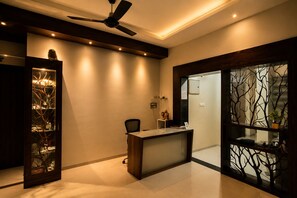 Un espacio de oficina moderno con escritorio, silla, ventilador de techo y paneles de vidrio decorativos.