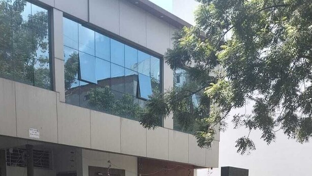 A building with a sign for 'HOTEL MG' and a contact number. There is a car parked in front.