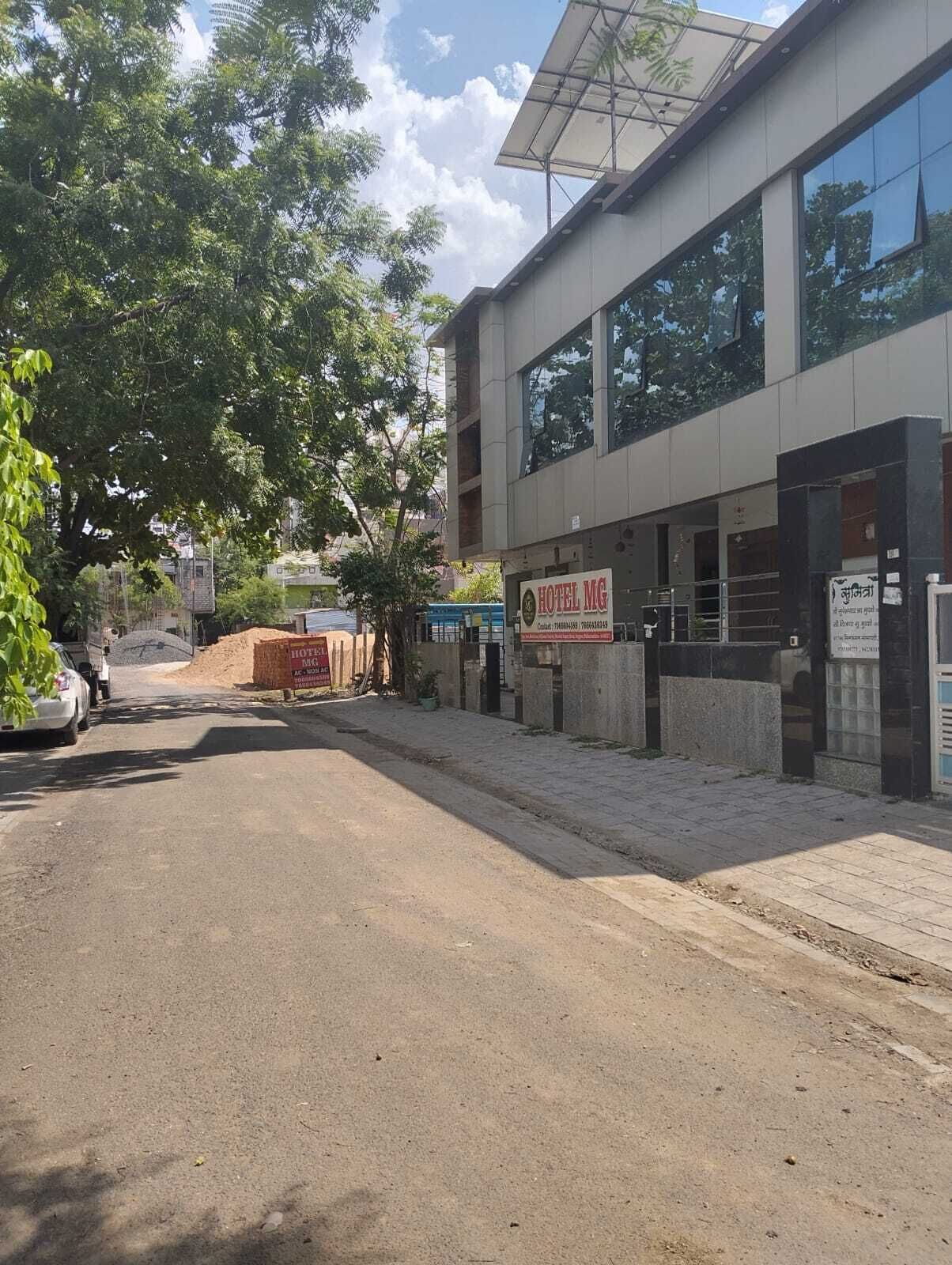 En modern byggnad med en skylt som visar ”HOTEL MG” och en asfalterad entré.