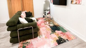 A modern living room with a sofa, a TV, and artwork on the wall. - Pink Luxe Retreat In Downtown Dallas (Dallas)