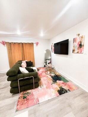 Ein modernes Wohnzimmer mit einer Couch, einem Fernseher und Kunstwerken an der Wand.