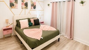 Une chambre à coucher avec un lit, des tables de chevet, une plante fixée au mur et un luminaire au plafond.