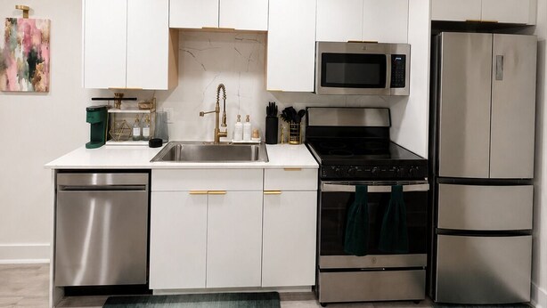 A modern kitchen with white cabinetry, stainless steel appliances, and a green rug. - Pink Luxe Retreat In Downtown Dallas (Dallas)