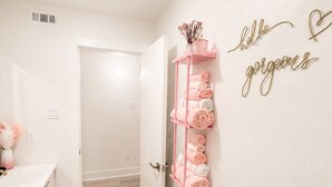 A bathroom with a white sink, a pink towel rack, a red rug, and a wall sign that says 'hello gorgeous'. - Pink Luxe Retreat In Downtown Dallas (Dallas)