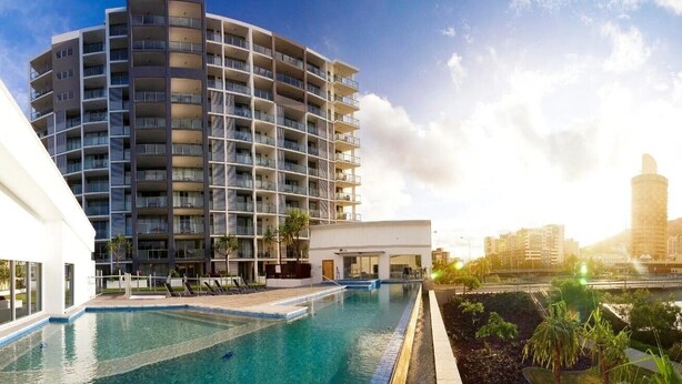 Ein modernes Hotel mit Pool, einem geschwungenen Gebäude und Blick auf die Stadtlandschaft.