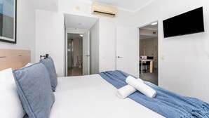 Ein Hotelzimmer mit Bett, Fernseher, Klimaanlage und einer Tür zum Badezimmer.
