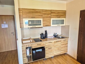 A compact kitchen with wooden cabinets, a built-in microwave, a coffee maker, and a dishwasher. - SeeSpiegel 369 – The Slow Down Apartment by Interhome (Faaker See)
