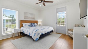 Une chambre à coucher avec un lit, un ventilateur de plafond, une fenêtre et une porte.