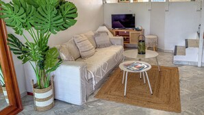 Een woonkamer met een bank, een salontafel, een televisie en een grote plant.