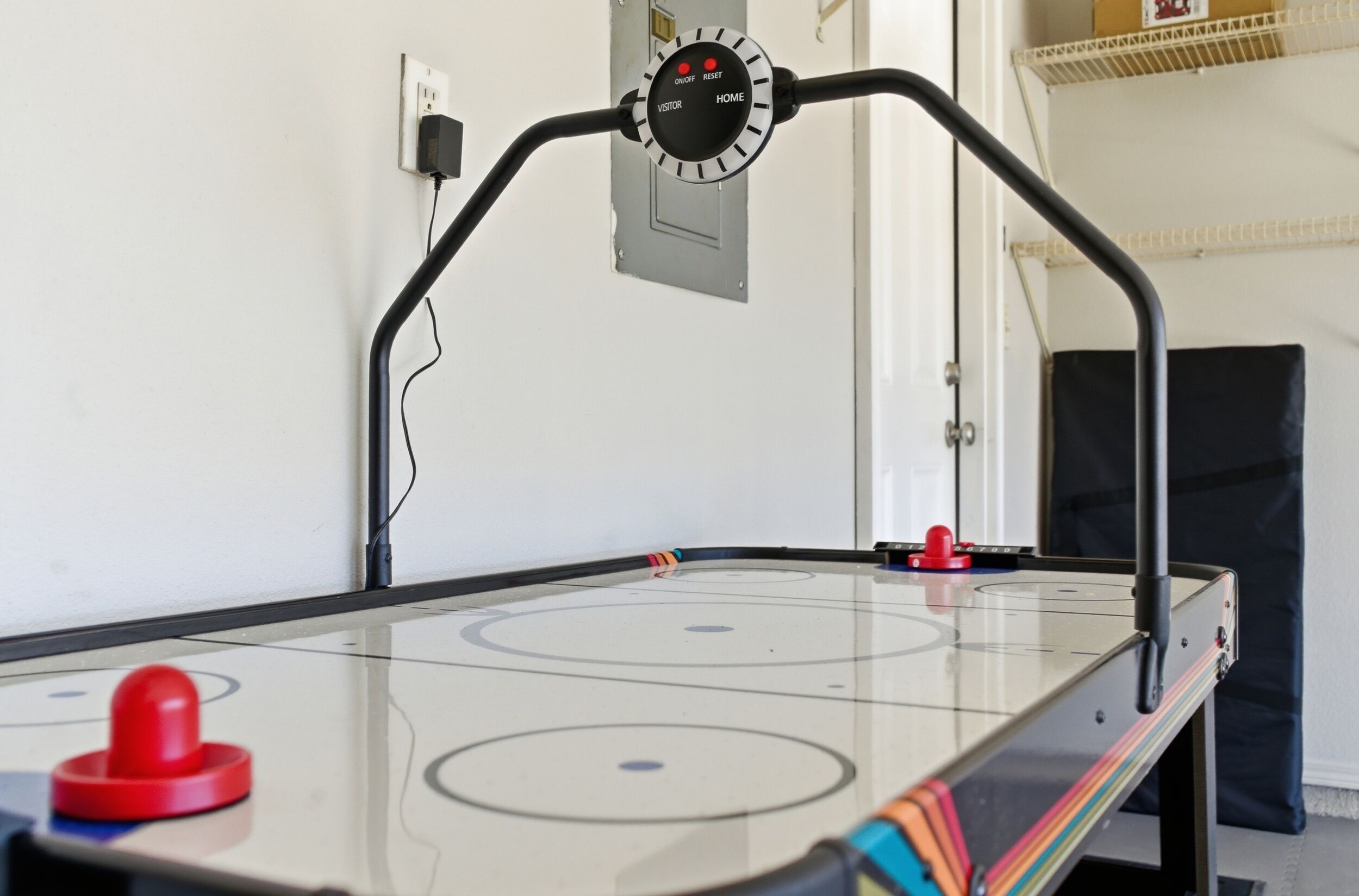 Un juego de hockey de mesa con un panel de control, un disco rojo y un cable.