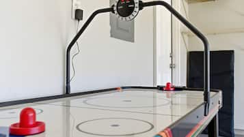 Un juego de hockey de mesa con un panel de control, un disco rojo y un cable.