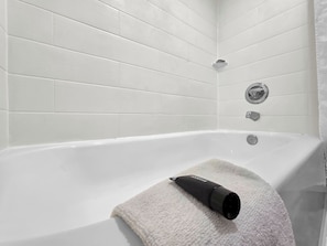Un baño moderno con paredes de azulejos blancos y una bañera.