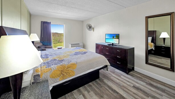 Ein Hotelzimmer mit Bett, Schminktisch, Fernseher, Spiegel und einem Fenster mit Blick.