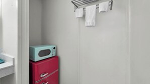 Ein Badezimmer mit einem weißen Waschbecken, einem roten Schrank, einer türkisblauen Mikrowelle und einem Handtuchhalter mit weißen Handtüchern.