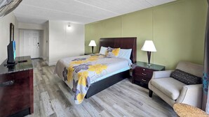 Ein Hotelzimmer mit Bett, Nachttischen, Schreibtisch, Stuhl und Standventilator.