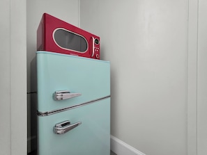 A light blue vintage refrigerator with a red microwave on top, featuring a digital display and control buttons.