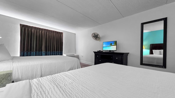 Een hotelkamer met twee bedden, een televisie, een bureau en een grote spiegel.