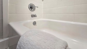 Une salle de bain avec une baignoire blanche, une serviette et un robinet fixé au mur.