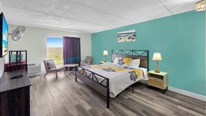 Une chambre à coucher avec un lit, des tables de chevet, un bureau, une chaise et une fenêtre avec des rideaux.