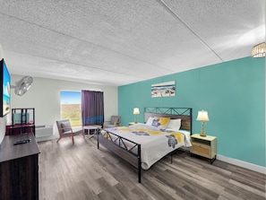 A bedroom with a bed, bedside tables, a desk, a chair, and a window with curtains.