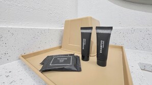A tray with a black soap pouch, two black shampoo tubes, and a beige tray on a speckled countertop. - Crystal Palace Resort - Family Suite King (Port Bolivar)