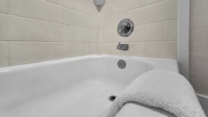 A modern bathroom with a freestanding bathtub, a towel rack, and a wall-mounted light fixture.