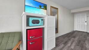A room with a red refrigerator, a teal microwave, and a green chair.
