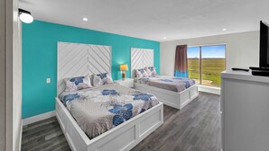 A bedroom with two beds, a TV, and a window with a view.