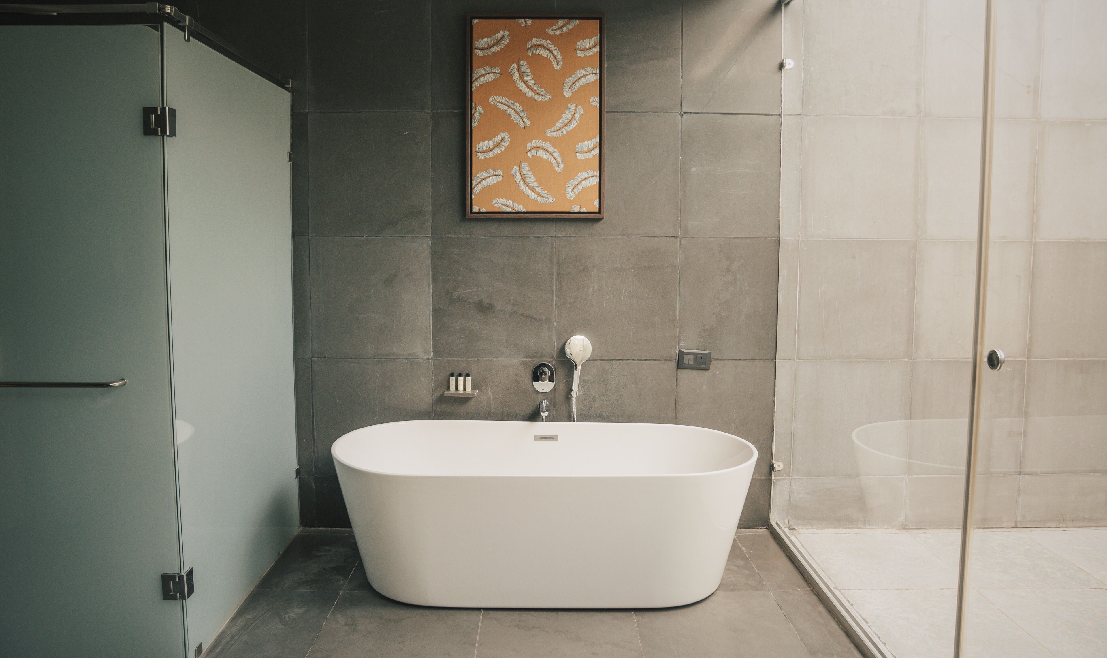 A modern bathroom with a freestanding bathtub, a glass shower enclosure, and a framed artwork on the wall.