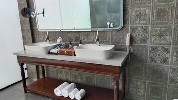 A bathroom with a double sink, a mirror above, a towel rack, and decorative wall tiles.