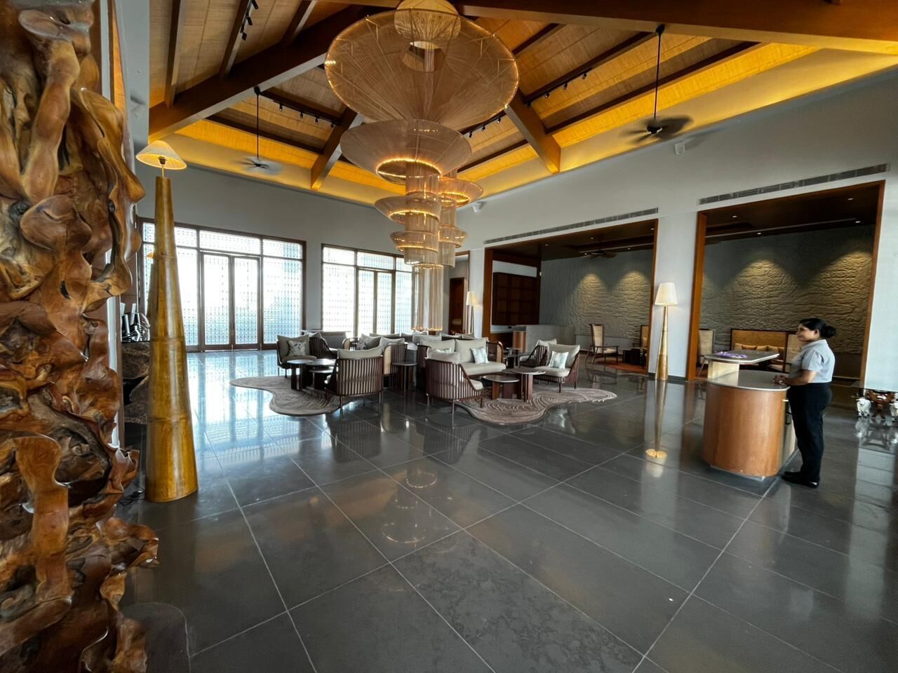 Un hallo espacioso con muebles modernos, una mesa de recepción y una gran escultura de madera.