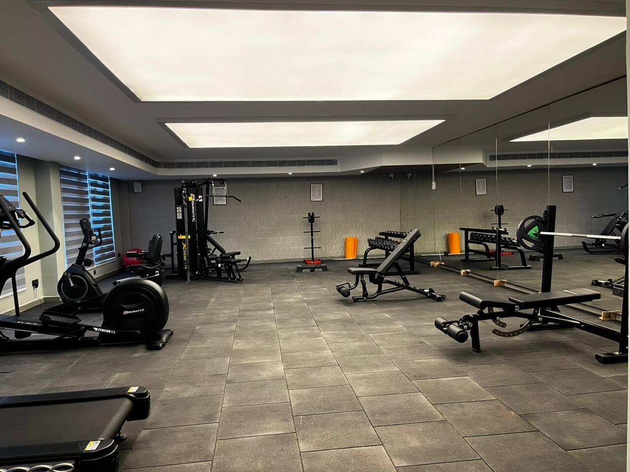 Un gimnasio con equipo de ejercicio variado, incluyendo cintas de correr, máquinas de pesas y pesas libres.