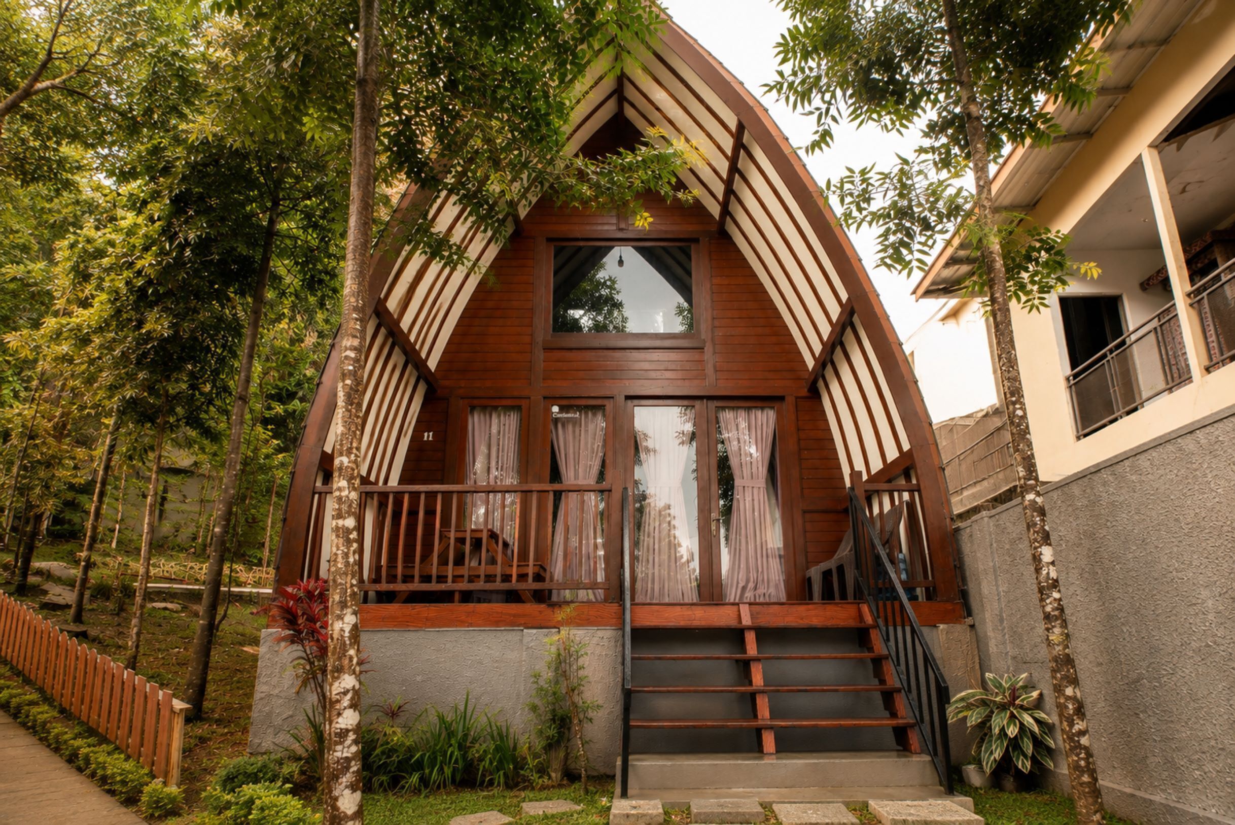 A house with a steeply pitched roof, a wooden front porch with a railing, and a staircase leading to the entrance.