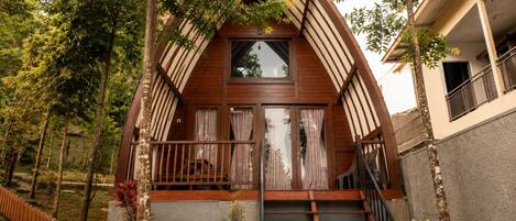A house with a steeply pitched roof, a wooden front porch with a railing, and a staircase leading to the entrance.