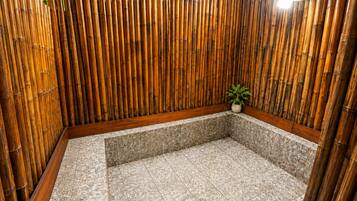 A spa area with a tiled floor, wooden wall, and a small plant.