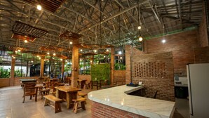 A spacious indoor area with high ceilings, exposed beams, and brick walls. There are wooden tables and benches, a marble counter, and large windows allowing natural light. - Savia Hotel & Resort Ciater (Ciater)