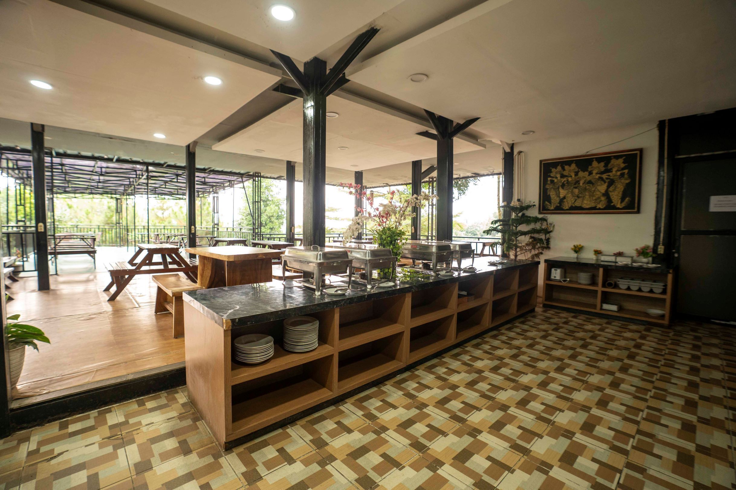 A spacious cafe with a central island counter, wooden tables, and a patterned floor.