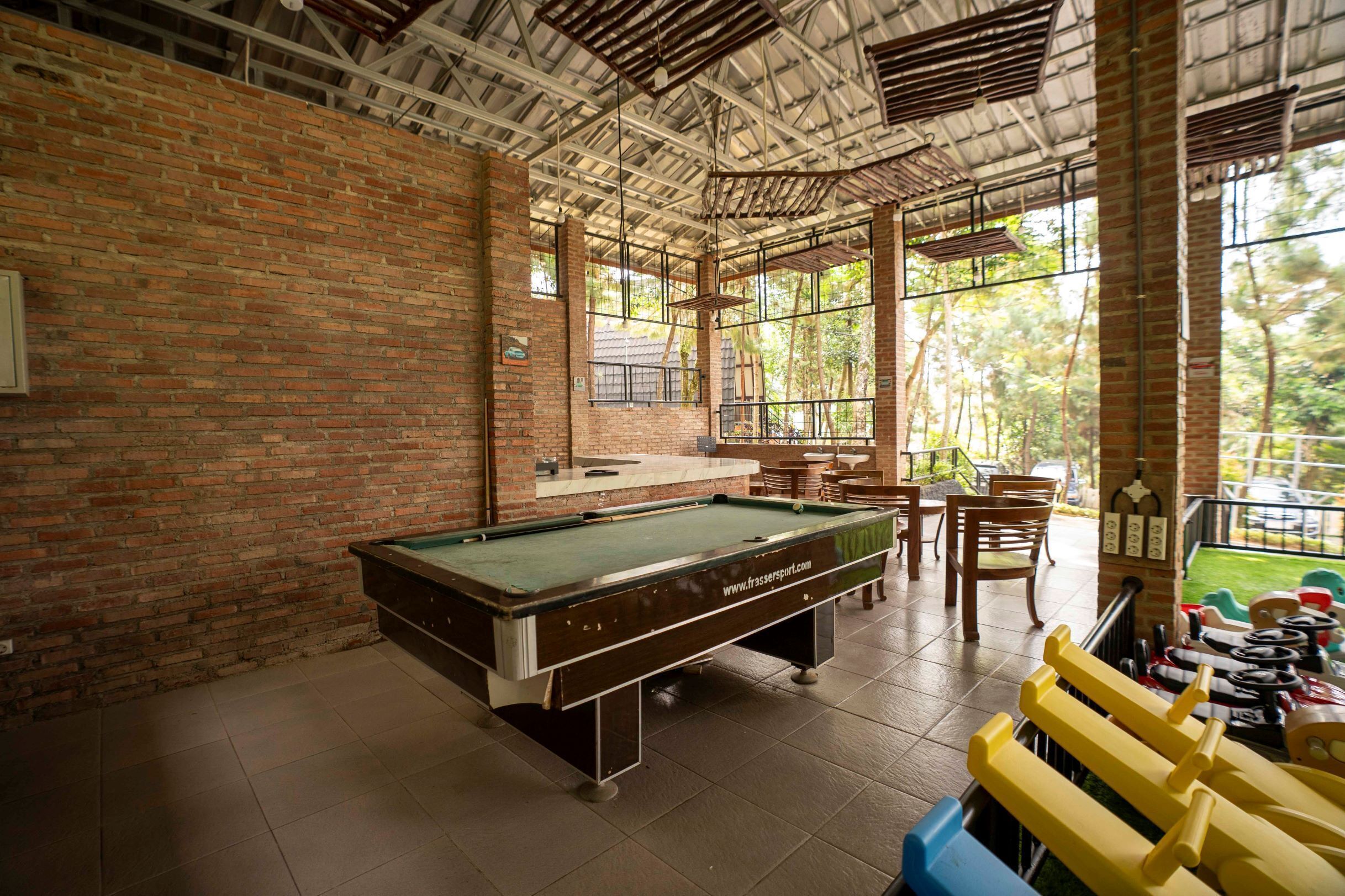 A billiards room with a pool table, chairs, and a small bar area.